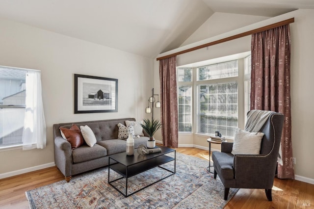 living area with baseboards, wood finished floors, and vaulted ceiling