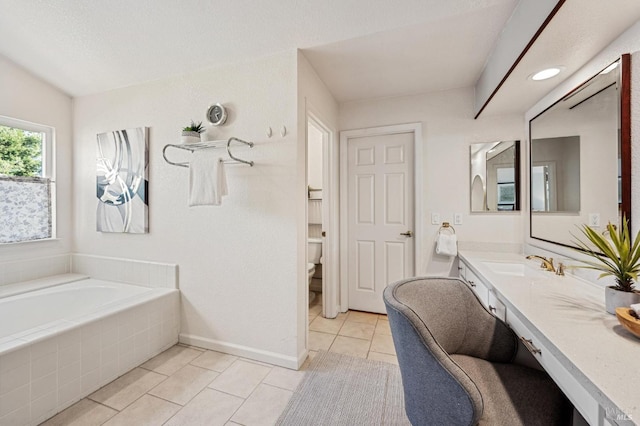 full bath featuring tiled bath, tile patterned flooring, baseboards, toilet, and vanity