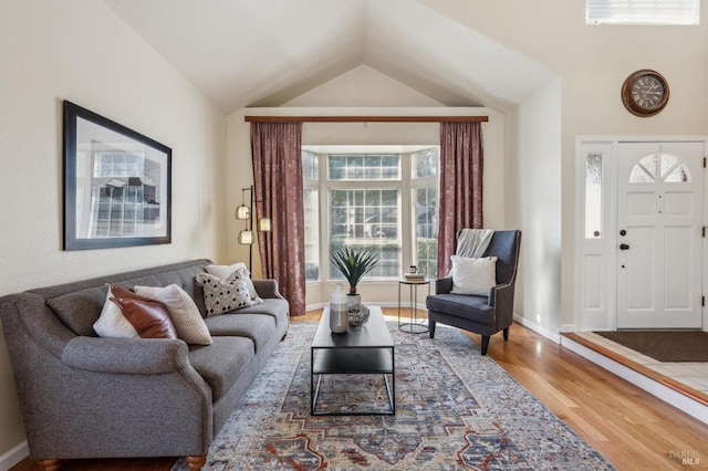 living room featuring lofted ceiling, wood finished floors, and baseboards