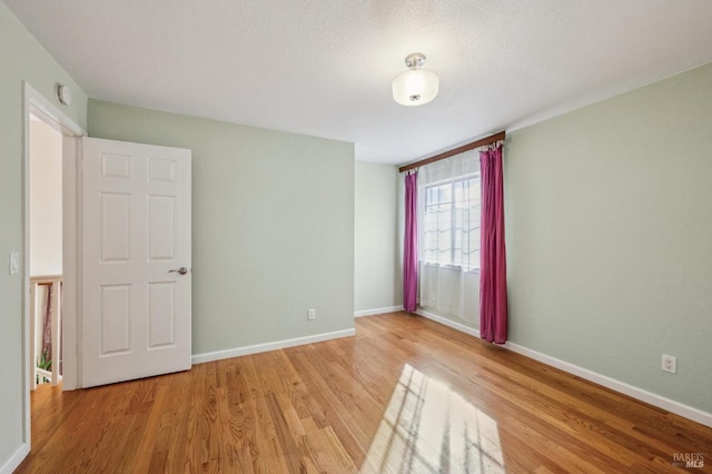 empty room with light wood-type flooring and baseboards