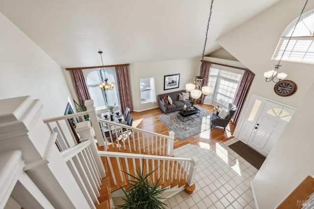 tiled foyer entrance featuring stairs, a notable chandelier, and high vaulted ceiling