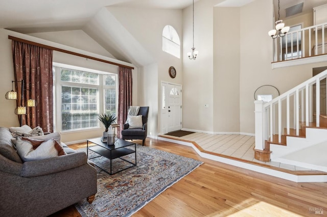 living room featuring stairway, wood finished floors, visible vents, baseboards, and a notable chandelier