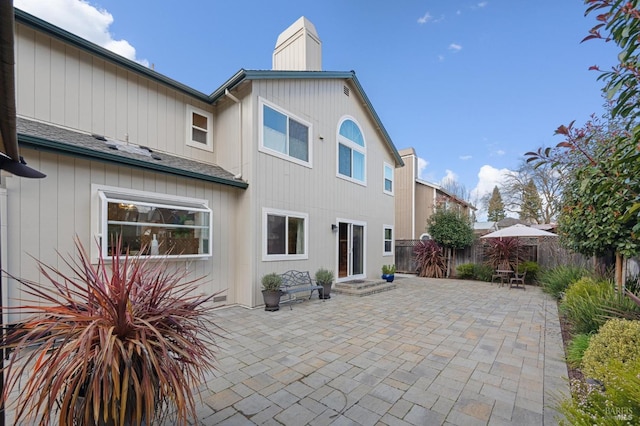 back of house featuring a patio, a chimney, and fence