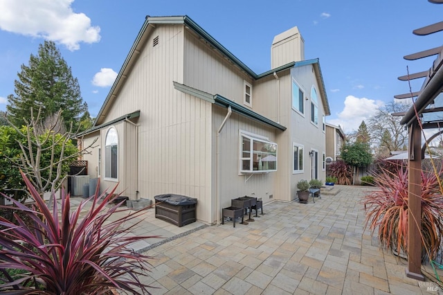 rear view of property featuring central air condition unit, fence, a chimney, and a patio area