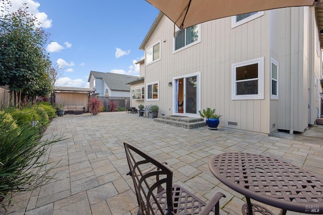 rear view of house with outdoor dining space, a patio, an outbuilding, a fenced backyard, and crawl space