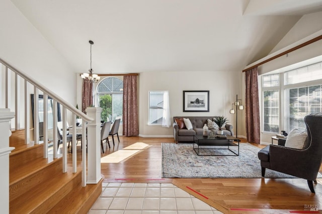 living room featuring a chandelier, light tile patterned floors, stairs, and vaulted ceiling