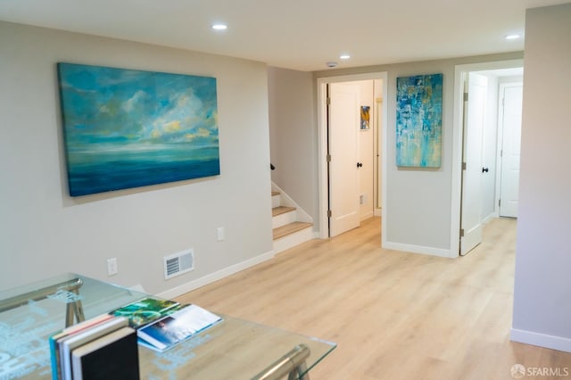 living area with light wood-type flooring, stairway, baseboards, and visible vents