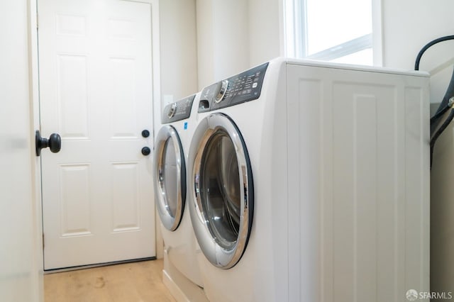 clothes washing area featuring laundry area, light wood-style flooring, and separate washer and dryer