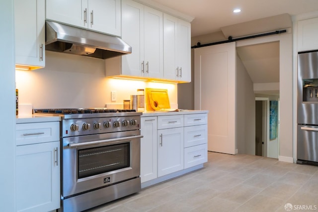 kitchen featuring a barn door, appliances with stainless steel finishes, light countertops, under cabinet range hood, and white cabinetry