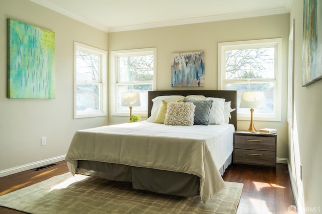 bedroom with dark wood-style flooring, visible vents, crown molding, and baseboards