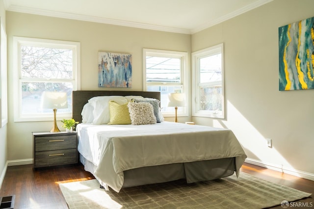 bedroom featuring dark wood-type flooring, multiple windows, ornamental molding, and visible vents