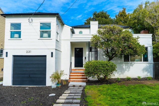 view of front of home with a chimney, an attached garage, and stucco siding