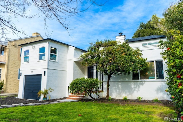 view of front of house with an attached garage, a chimney, a front lawn, and stucco siding