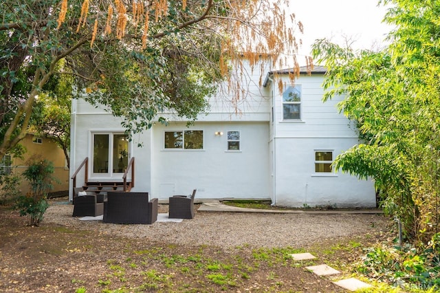 rear view of house featuring a patio area, an outdoor living space, and stucco siding