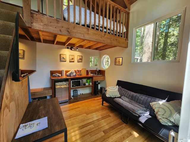 living area featuring beam ceiling, baseboards, and wood finished floors