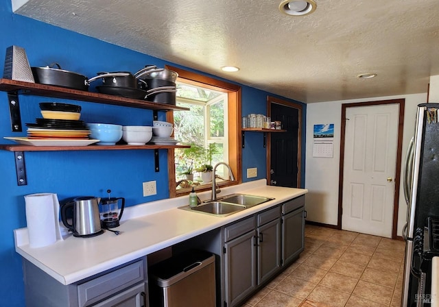 kitchen featuring light tile patterned floors, stainless steel appliances, a textured ceiling, light countertops, and a sink