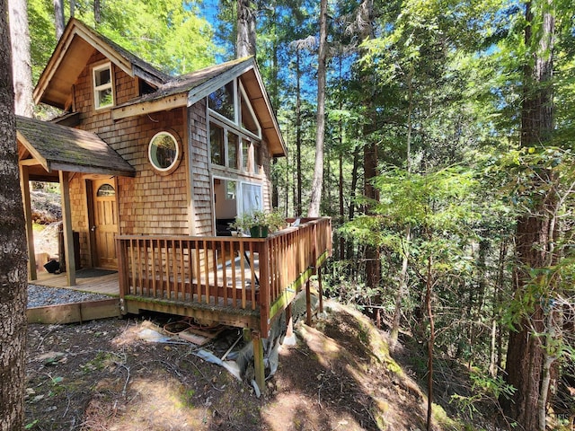 exterior space with roof with shingles and a wooden deck