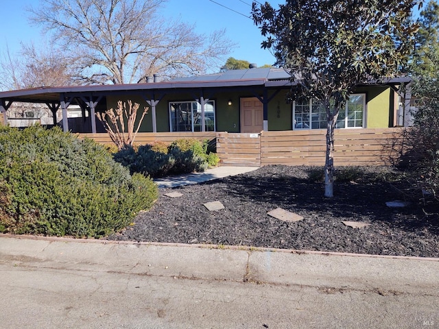 ranch-style home with stucco siding, fence, and solar panels