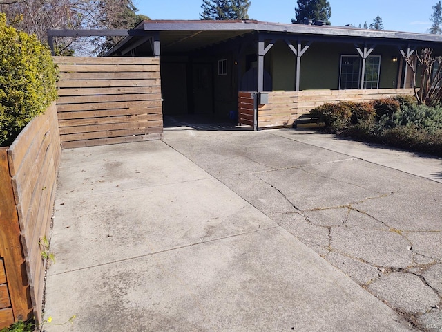 view of front facade with driveway, a carport, and fence