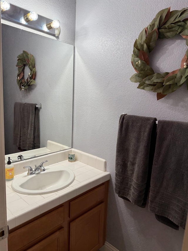 bathroom with a textured wall and vanity