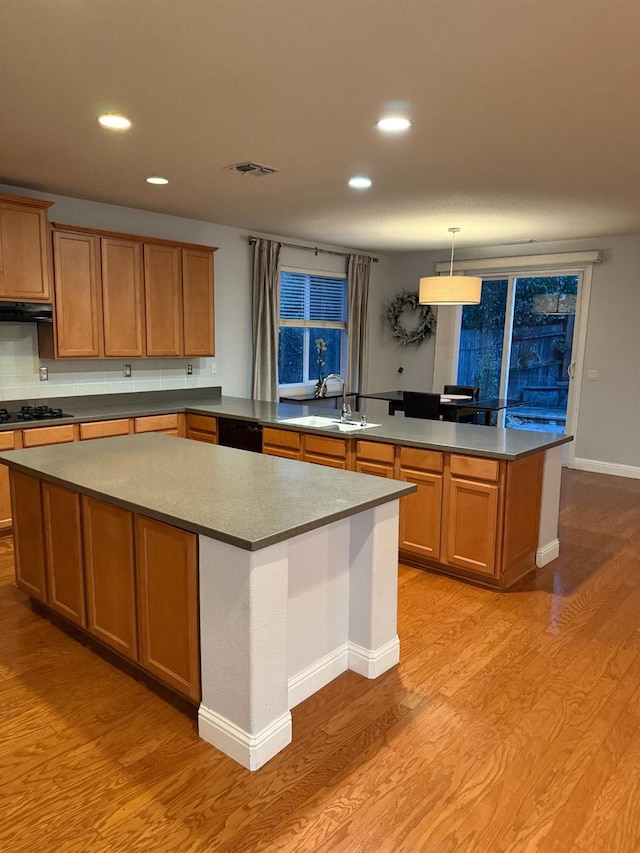 kitchen with black appliances, light wood-style floors, a sink, and a center island