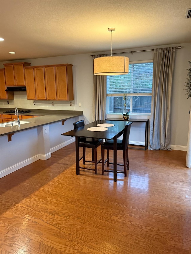 dining space with a textured ceiling, recessed lighting, wood finished floors, visible vents, and baseboards