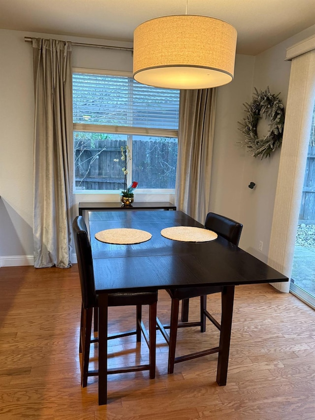 dining room with baseboards, wood finished floors, and a healthy amount of sunlight