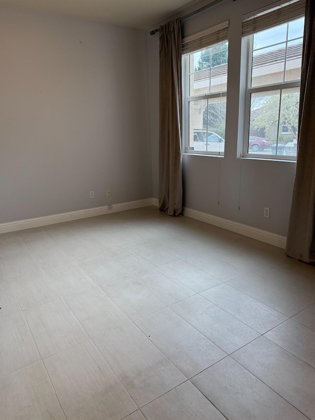 unfurnished room featuring a healthy amount of sunlight, light tile patterned floors, and baseboards