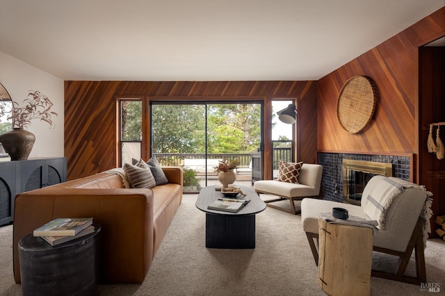 living room with a tile fireplace, carpet floors, and wood walls