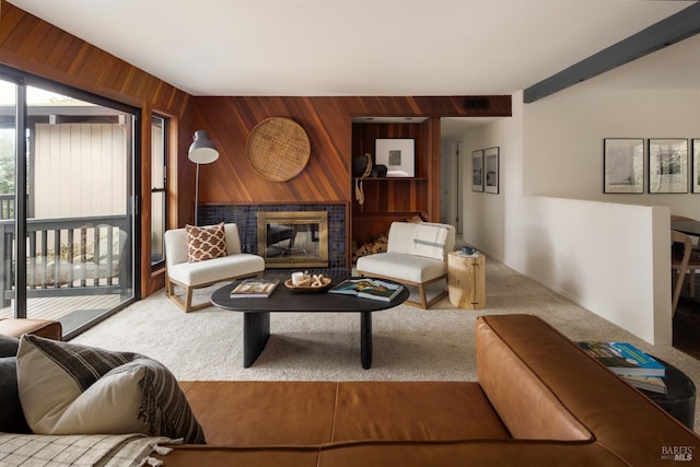 living room featuring a tiled fireplace, carpet, and wood walls