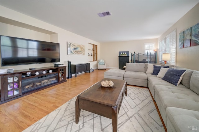 living area featuring wood finished floors, visible vents, and baseboards