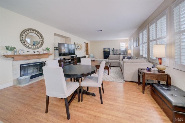 dining space featuring light wood-style floors, visible vents, a fireplace, and baseboards