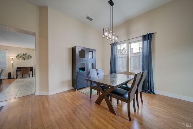 dining room featuring light wood-style floors, a chandelier, visible vents, and baseboards