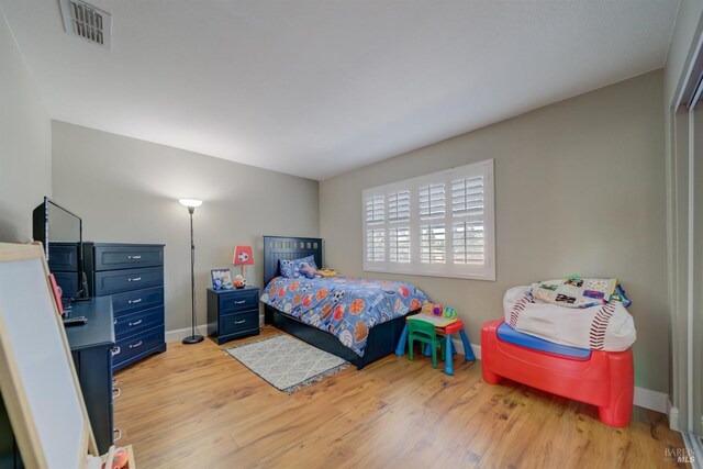 bedroom featuring light wood-style flooring, visible vents, and baseboards