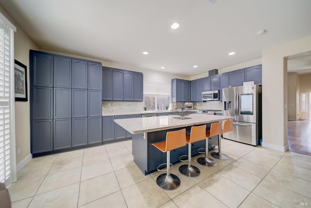 kitchen featuring light tile patterned floors, appliances with stainless steel finishes, a kitchen bar, and a center island