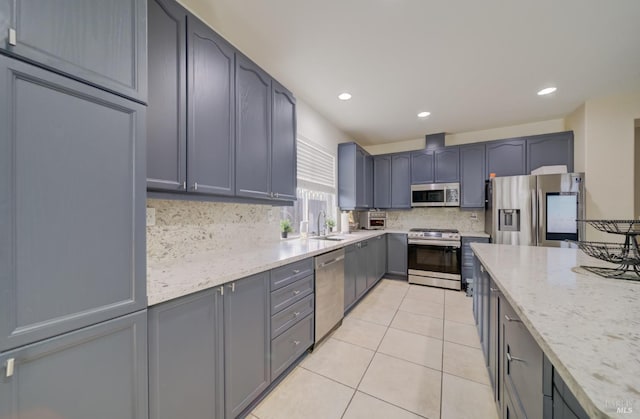 kitchen featuring backsplash, appliances with stainless steel finishes, light tile patterned flooring, a sink, and light stone countertops