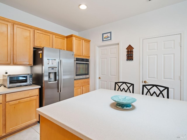 kitchen with appliances with stainless steel finishes, light tile patterned floors, and light brown cabinetry