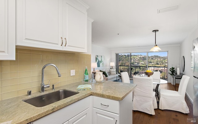 kitchen with light stone counters, sink, decorative light fixtures, and white cabinets