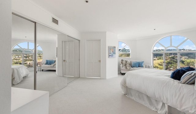 bedroom featuring crown molding, light colored carpet, and a closet