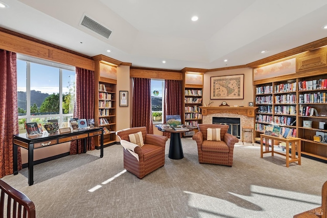 sitting room with a raised ceiling, ornamental molding, light carpet, and built in shelves