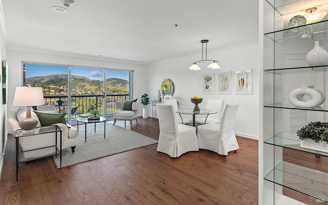 dining space featuring dark wood-type flooring, ornamental molding, and a mountain view