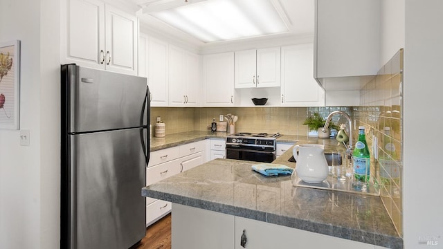 kitchen featuring sink, stainless steel fridge, electric range, white cabinets, and kitchen peninsula