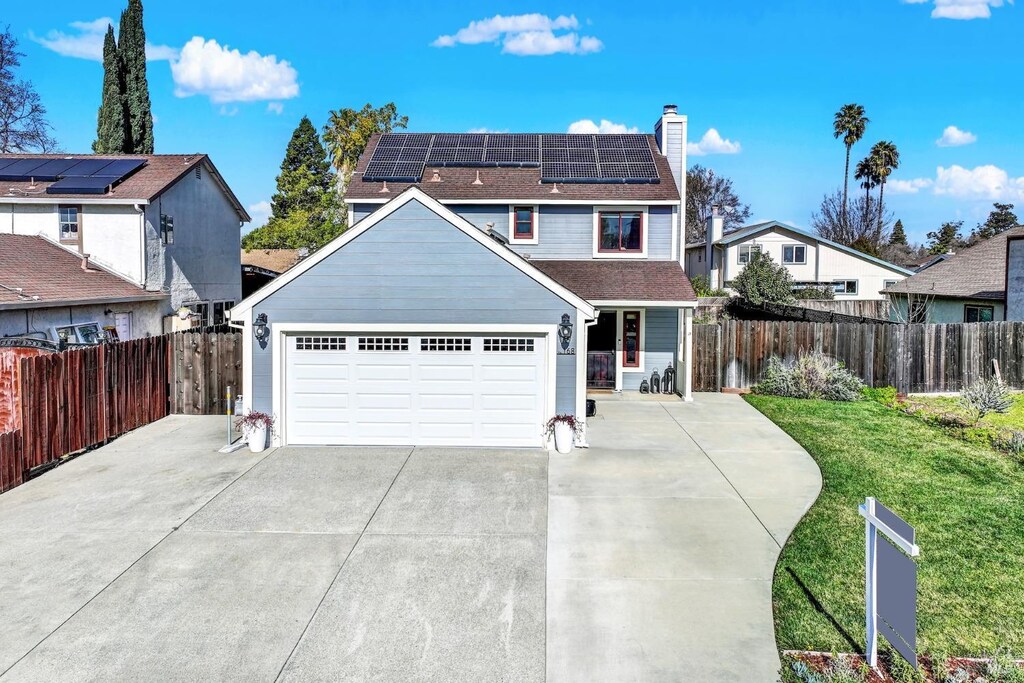 view of front facade with a garage, a front lawn, and solar panels