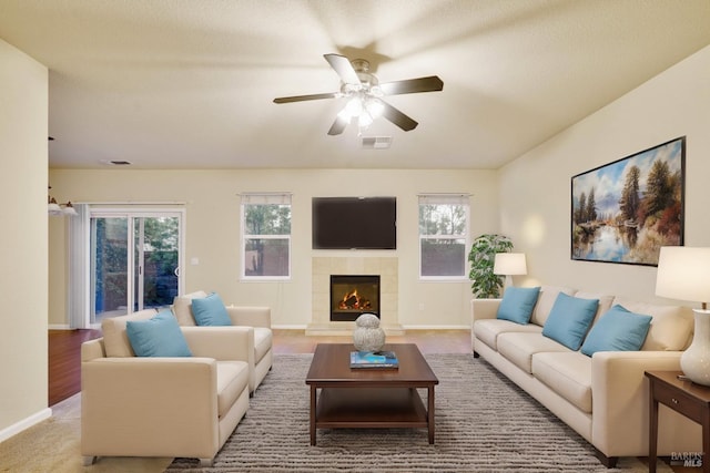 living room with ceiling fan, carpet, and a tile fireplace