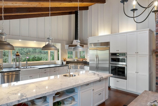 kitchen with white cabinets, stainless steel appliances, sink, and dark stone countertops