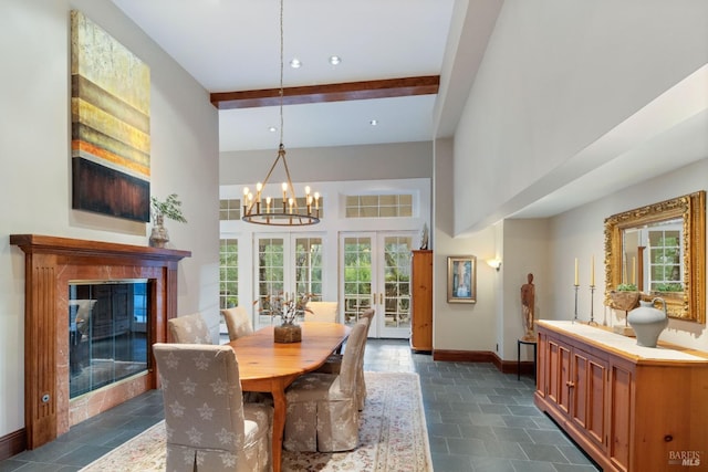 dining room with beam ceiling, a towering ceiling, a high end fireplace, french doors, and a chandelier