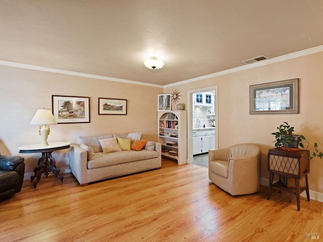 living room featuring ornamental molding, sink, and light hardwood / wood-style floors