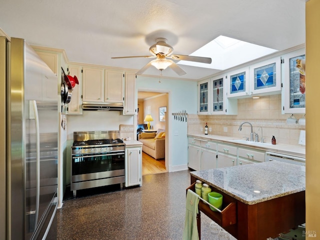 kitchen with sink, ceiling fan, appliances with stainless steel finishes, white cabinetry, and tasteful backsplash