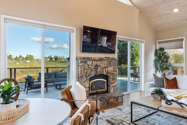 living room featuring wooden ceiling, a healthy amount of sunlight, a stone fireplace, and wood finished floors