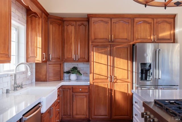 kitchen with brown cabinets, appliances with stainless steel finishes, light countertops, and a sink